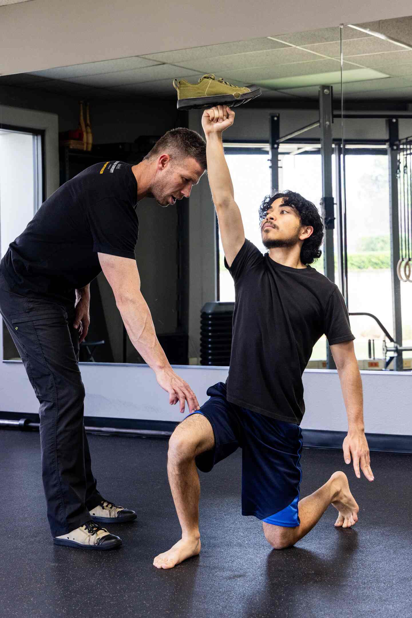 Coach Mike guiding a client's kettlebell form with hands-on instruction